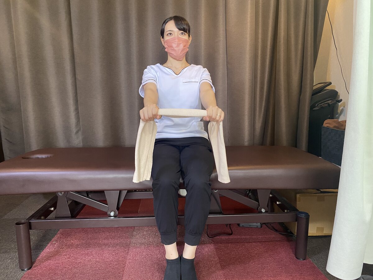 椅子に座ってタオルを両手で持つ背中ストレッチの開始姿勢